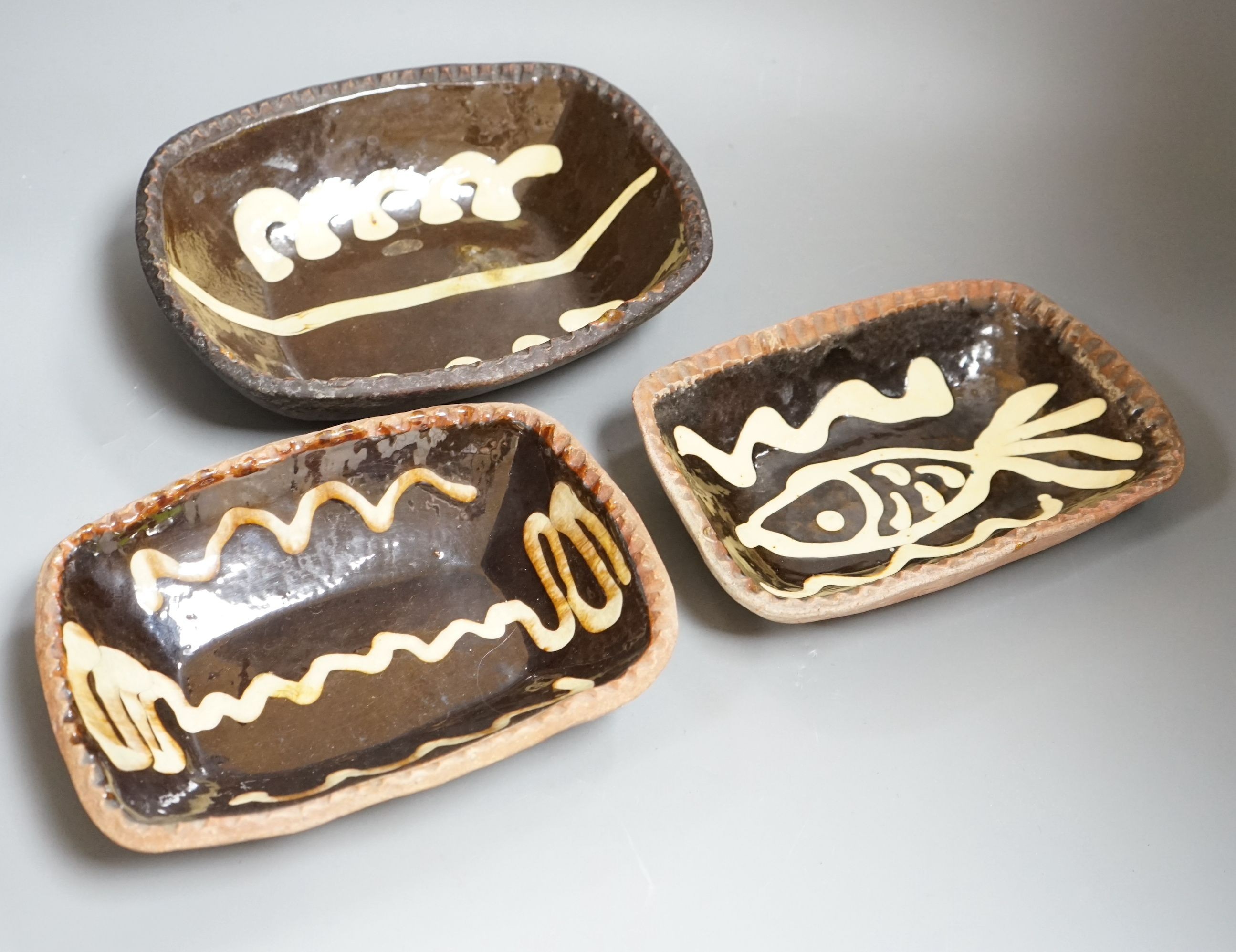 Winchcombe pottery, three press moulded slipware dishes, one with Ray Finch maker’s stamp, largest 26.5cm wide